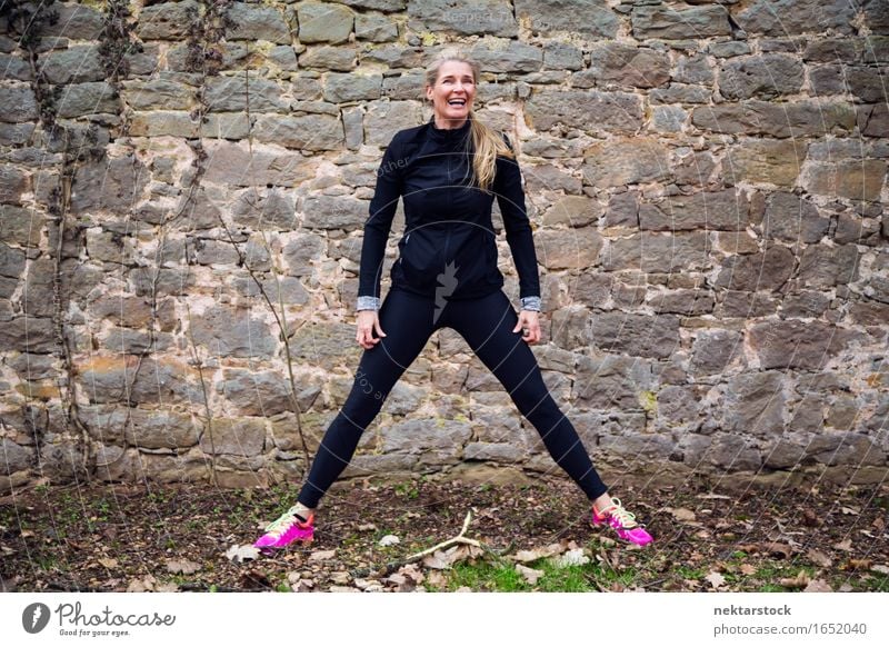 Woman stretching her body in front of ancient wall in park Lifestyle Happy Body Wellness Sports Human being Adults Park Stone Fitness Smiling Athletic