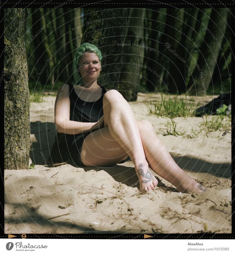 young woman sitting in forest on beach with legs crossed and turquoise hair smiling Joy Trip Summer Young woman Youth (Young adults) Legs Feet 18 - 30 years