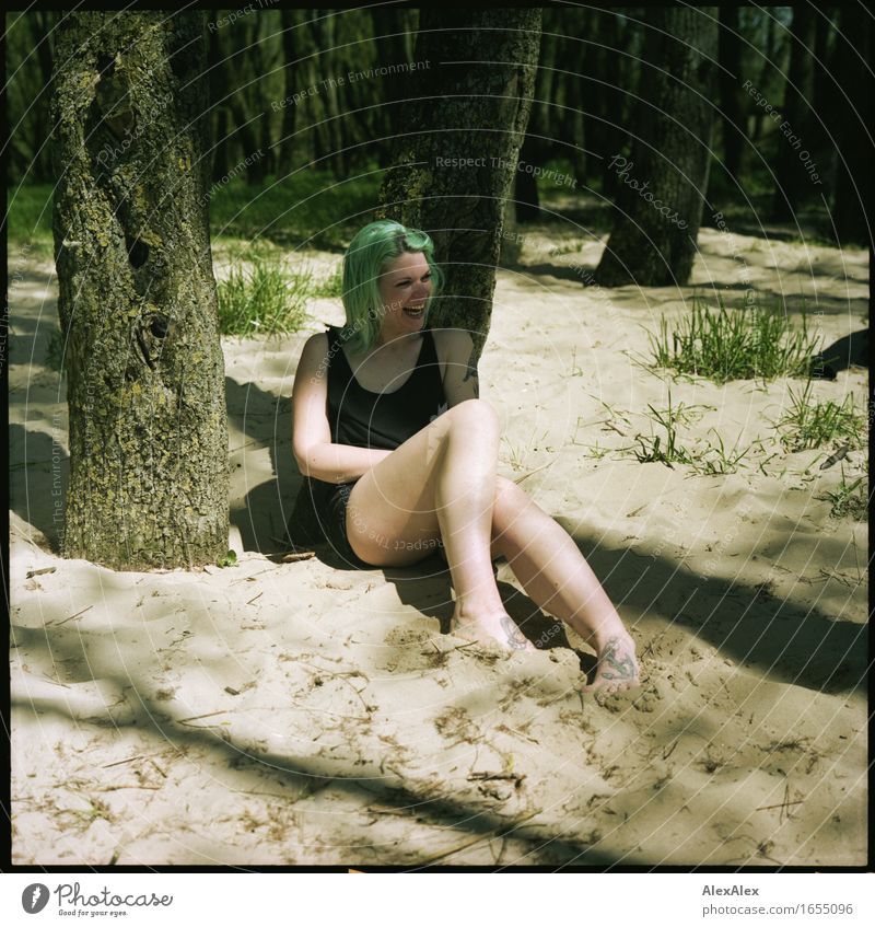 Young woman with turquoise hair sits barefoot in forest on beach and laughs loudly Life Trip Summer vacation Youth (Young adults) Body Legs 18 - 30 years Adults