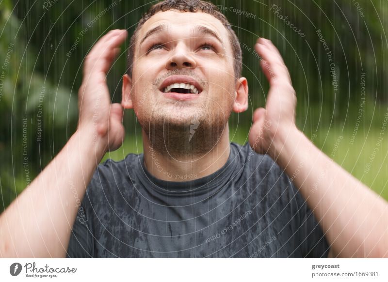 Young unshaven man getting wet under the rain. Lifestyle Face Human being Young man Youth (Young adults) Man Adults Arm 1 18 - 30 years Weather Storm Rain Park