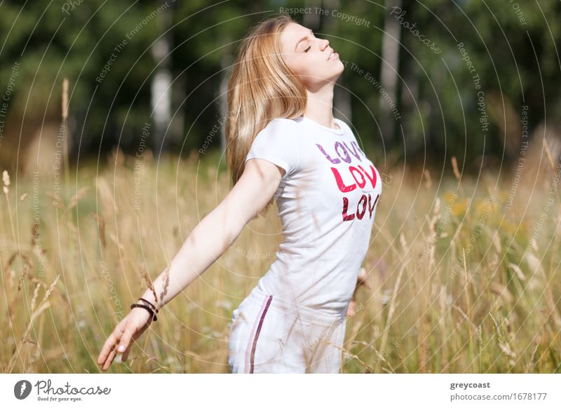 An attractive young girl falling in love standing in a crop field with her arms outstretched and eyes closed enjoying freetime Lifestyle Happy Beautiful