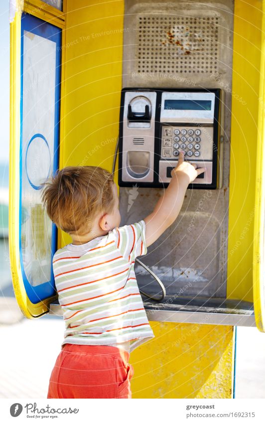 Young boy talking to the phone in a yellow telephone booth Child To talk Telephone Cellphone Baby Boy (child) Infancy 1 Human being 3 - 8 years Street Blonde
