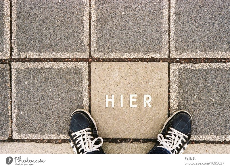 H I E R Feet Concrete slab Pedestrian Footpath Footwear Stone Characters Capital letter Language Stand Wait Sharp-edged Firm Under Warmth Gray Unwavering