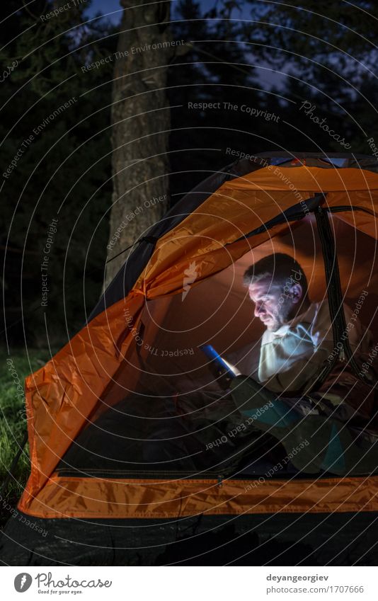 Man watching his smartphone in a tent Lifestyle Happy Vacation & Travel Adventure Camping Summer Hiking Telephone PDA Human being Adults Friendship Forest Dark