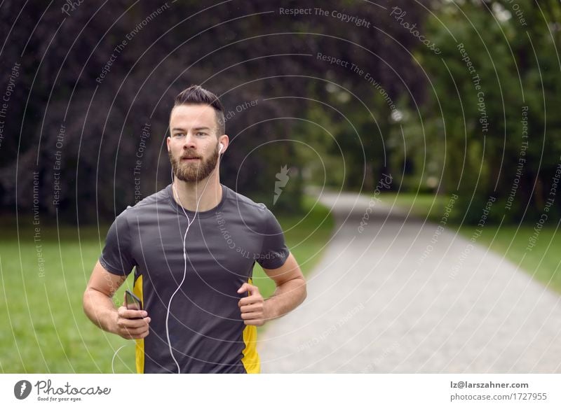 Fit young man jogging in a park Lifestyle Body Face Music Sports Jogging Man Adults 1 Human being 18 - 30 years Youth (Young adults) Fitness Listening Action