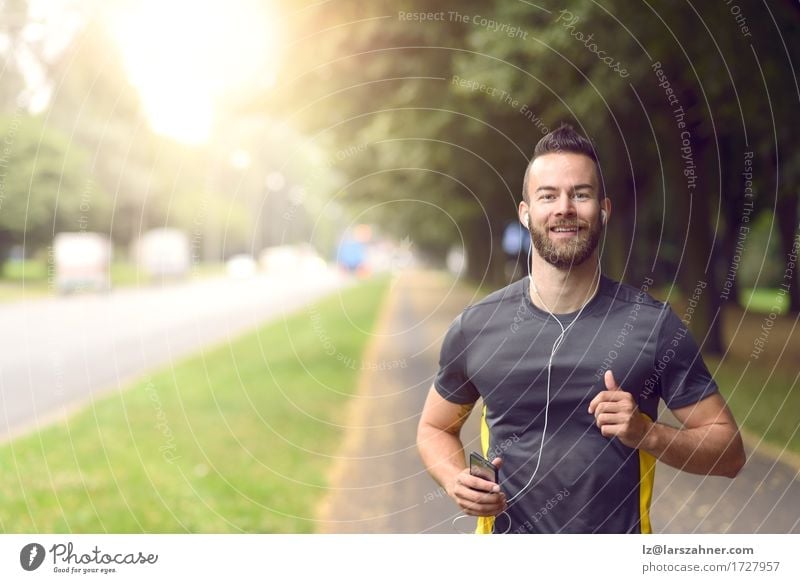 Man jogging along a tree lined sidewalk Lifestyle Happy Body Face Music Sports Jogging Masculine Adults 1 Human being 18 - 30 years Youth (Young adults) Fitness