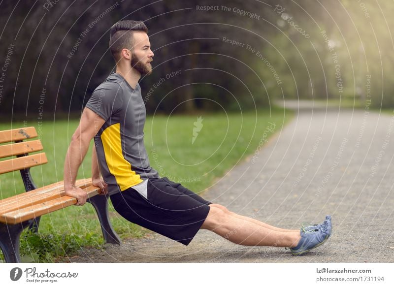 Young man exercising in a park Lifestyle Body Sports Man Adults 1 Human being Nature Park Beard Wood Fitness Athletic Modern Action Balance bearded Bench