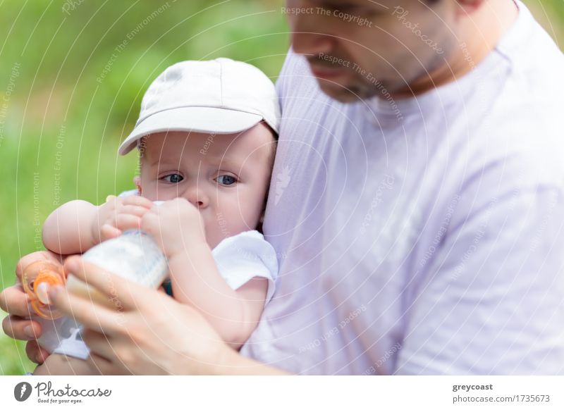 Caring father feeding his baby son from the bottle in the park Dinner Milk Bottle Garden Child Baby Boy (child) Young man Youth (Young adults) Parents Adults