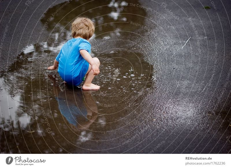 Child playing in a puddle Playing Human being Masculine Boy (child) 1 3 - 8 years Infancy Summer Autumn Weather Bad weather Rain Street T-shirt Water Crouch