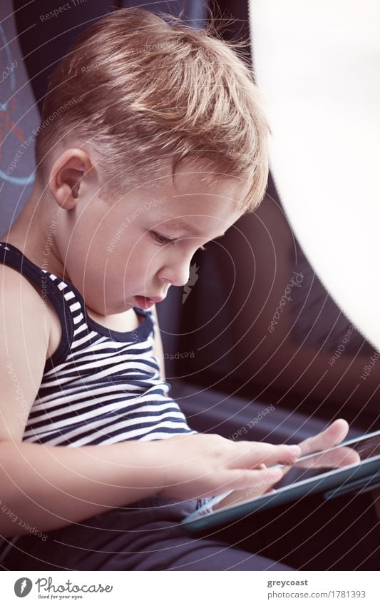 Little boy sitting by the window in the bus and using touch pad to entertain himself during the trip Joy Leisure and hobbies Playing Vacation & Travel Trip