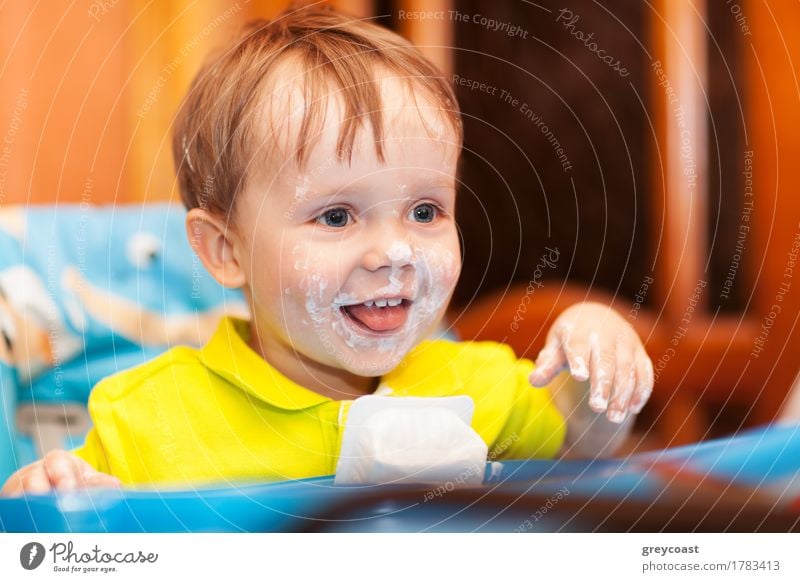 Close-up of shot of a happy cute boy sitting at feeding table, his face and hands dirty with cream yoghurt Yoghurt Nutrition Joy Happy Table Child Boy (child)