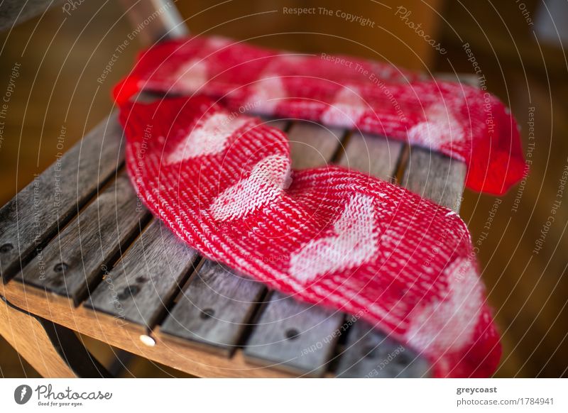 Close-up shot of a pair of red woollen socks with heart pattern lying on wooden chair Furniture Chair Woman Adults Warmth Balcony Garden Clothing Footwear Wood