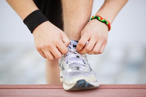 Close-up shot of man tying running shoes with foot on the bench. Getting ready before jogging. Going in for sports, healthy lifestyle Lifestyle Sports Jogging