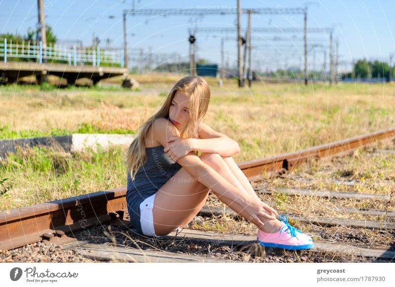 Lonely and sad teeneger girl sitting on rusty rail track in the countryside. Adolescense problems Summer Girl Woman Adults Youth (Young adults) Landscape
