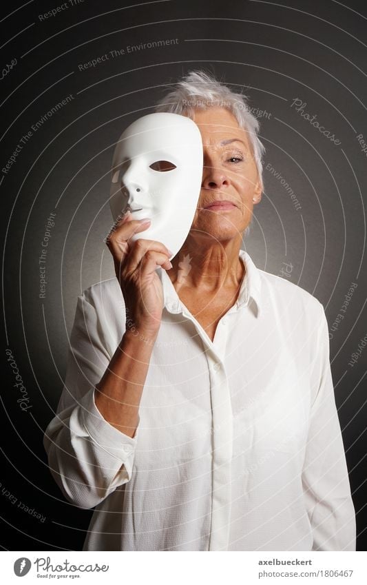 serious mature woman revealing face behind mask Leisure and hobbies Playing Human being Woman Adults Female senior Grandmother Senior citizen 1