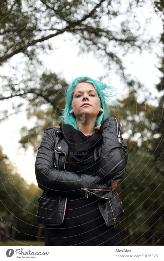 Young woman in black leather jacket and turquoise hair stands upright and looks down at camera Style Youth (Young adults) 18 - 30 years Adults Landscape