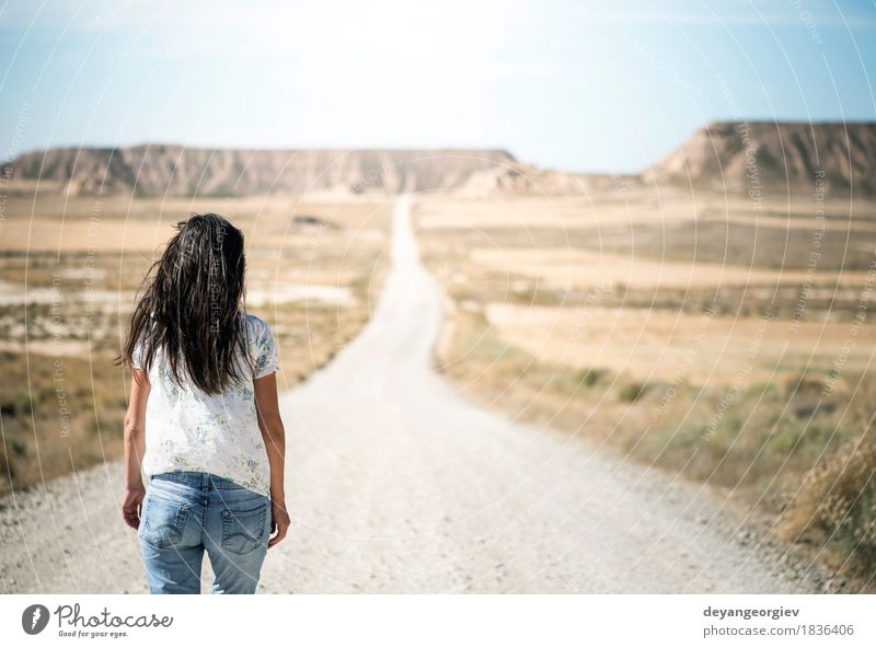 Woman walking on dirt road. Relaxation Mountain Hiking Adults Nature Landscape Earth Sky Park Hill Rock Street Jeans Blue Red movie Western sierra desert Valley