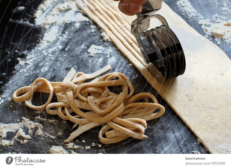 Making homemade taglatelle with a pasta rolling cutter Dough Baked goods Nutrition Italian Food Table Kitchen Tool Make Dark Fresh Tradition Ingredients manual