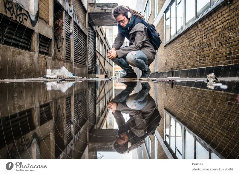 Woman with headphones in side alley in front of puddle, looks down Lifestyle Style Calm Adventure Freedom Human being Feminine Adults 1 30 - 45 years Water