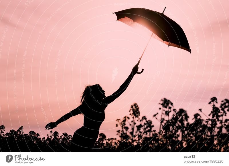 Detached woman in silhouette with umbrella flies into the future. Warm scene with flying girl. Shows the imagination and the departure to new horizons like climate change or mindfulness.
