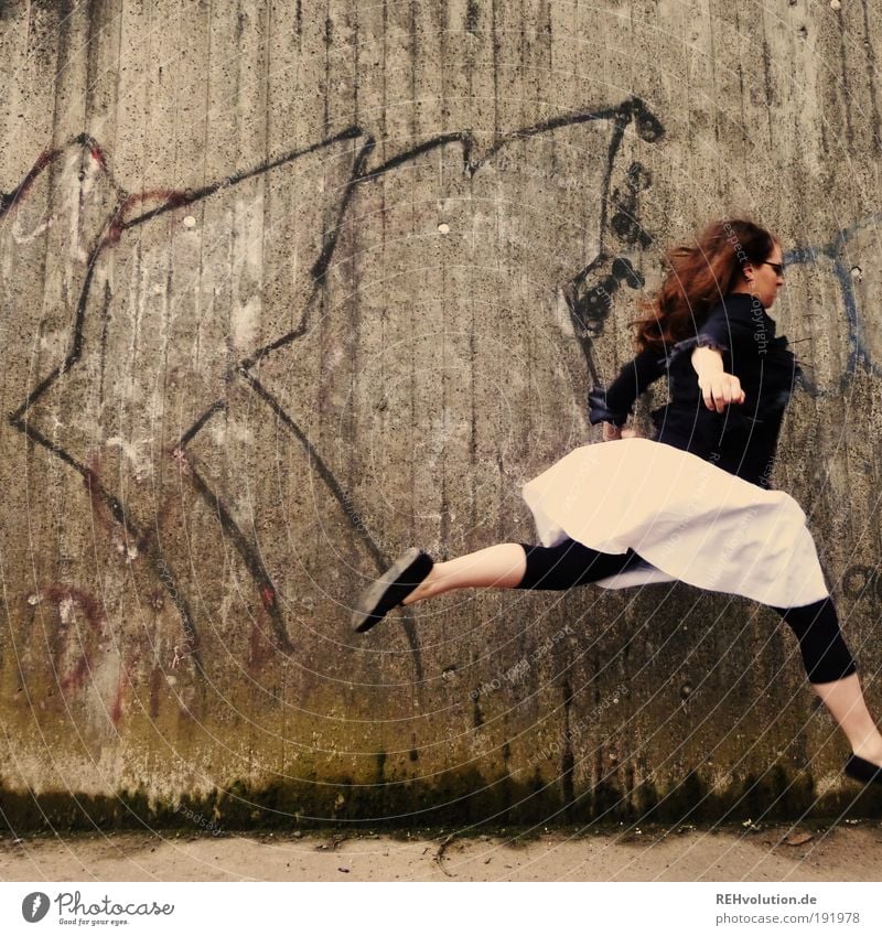 Woman jumps in front of a wall Human being Feminine Young woman Youth (Young adults) 1 18 - 30 years Adults Wall (barrier) Wall (building) Skirt Leggings