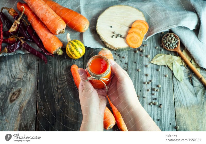 Jar of fresh carrot juice in female hand Vegetable Fruit Herbs and spices Juice Bottle Spoon Body Skin Health care Table Woman Adults Arm Hand 1 Human being