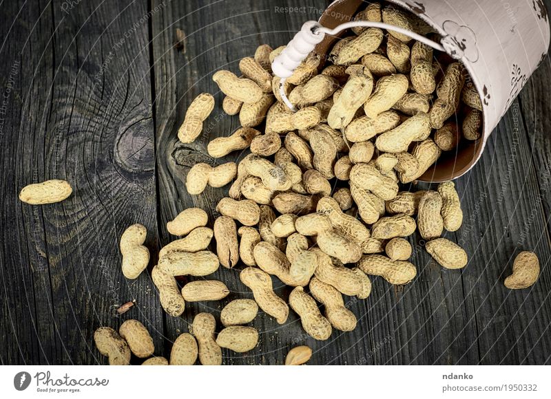 Spilling from white metal bucket of peanuts in the shell Food Vegetable Breakfast Diet Bowl Table Wood Metal Bright Above Yellow Gray White Peanut groundnut