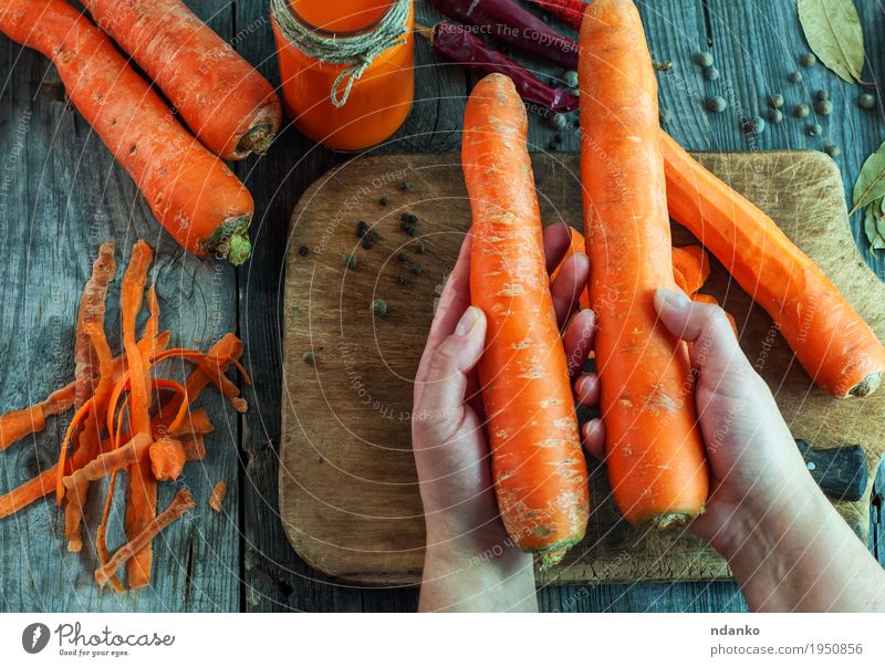 Two large ripe carrots lie in female hands Vegetable Nutrition Vegetarian diet Diet Beverage Juice Bottle Body Healthy Eating Table Woman Adults Hand Fingers 1