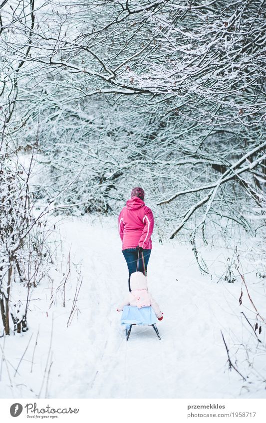 Woman pulling sledge with her little daughter Lifestyle Joy Trip Winter Snow Winter vacation Child Human being Baby Girl Adults Parents Mother