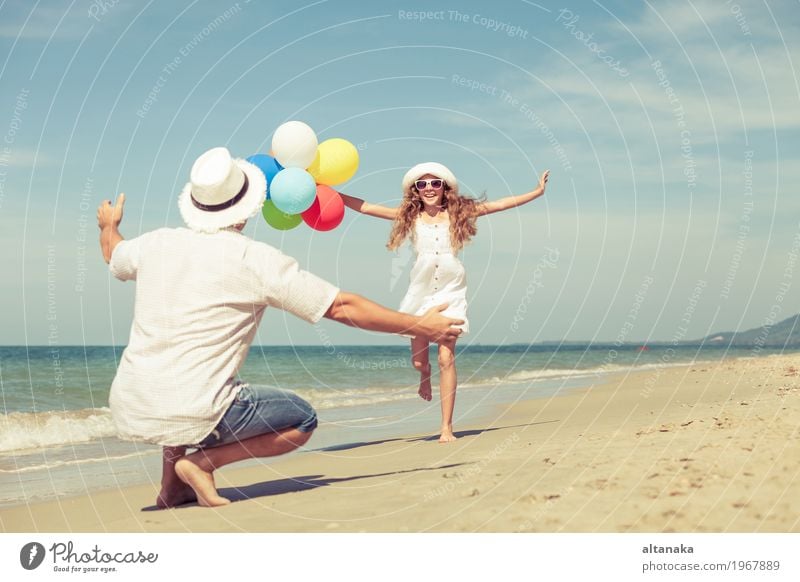 Father and daughter with balloons playing on the beach at the day time. Concept of friendly family. Lifestyle Joy Relaxation Leisure and hobbies Playing
