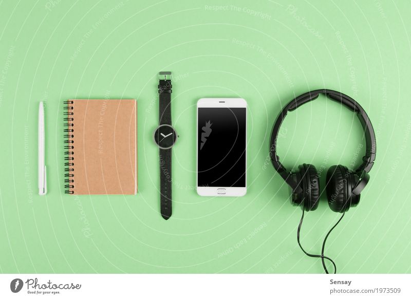 Smartphone, notepad, headphones on the color back Table Music Business Telephone PDA Computer Screen Technology Internet Media Paper Listening Above Green White