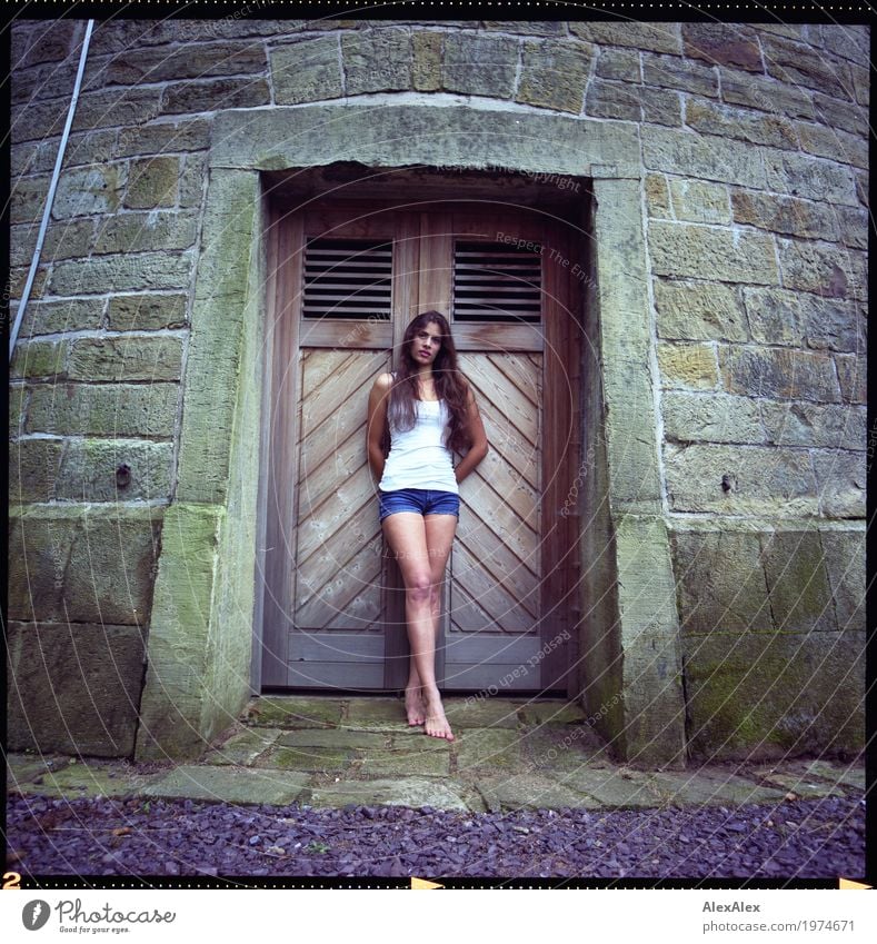 Young, slim, athletic woman in hot pants stands barefoot in front of a wooden door of a water tower Lifestyle pretty Tower Goal Young woman Youth (Young adults)