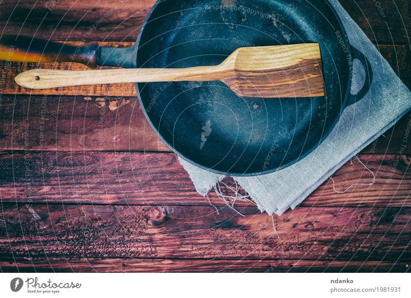Empty frying pan on a brown wooden surface Crockery Pan Table Kitchen Tool Cloth Wood Metal Above Clean Brown Black tableware Tablecloth spatula copy