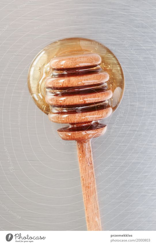 Close shot of honey dipper on a metal surface Food Candy Nutrition Organic produce Diet Wood Metal Drop Fresh Healthy Natural Above Gold White background drip