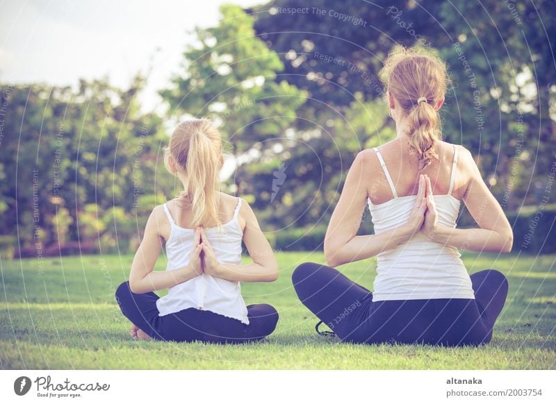 Mother and daughter doing yoga exercises on grass in the park at the day time Lifestyle Joy Happy Beautiful Body Wellness Harmonious Relaxation Meditation