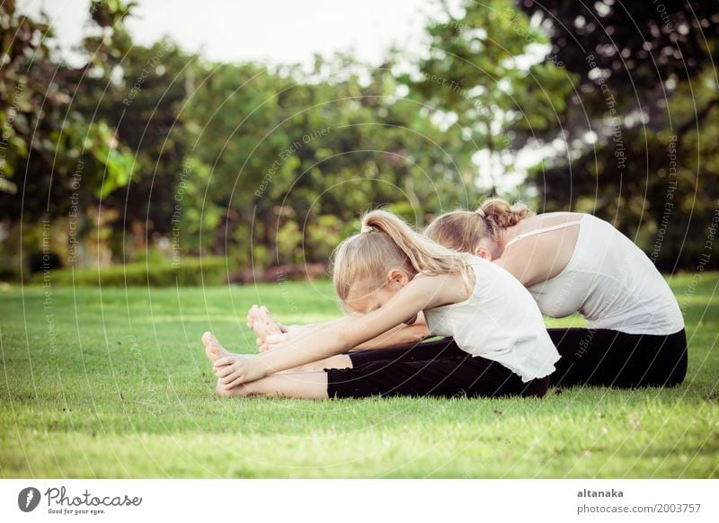 Mother and daughter doing yoga exercises on grass in the park at the day time Lifestyle Joy Happy Beautiful Body Wellness Harmonious Relaxation Meditation