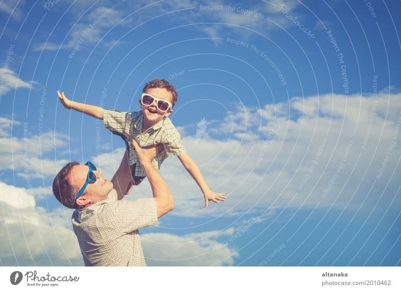Father and son playing in the park at the day time. Concept of friendly family. Picture made on the background of blue sky. Lifestyle Joy Relaxation
