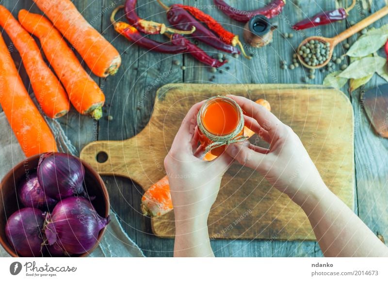 Women's hands hold a jar of carrot juice Vegetable Herbs and spices Nutrition Eating Drinking Cold drink Juice Bottle Spoon Table Woman Adults Hand 1