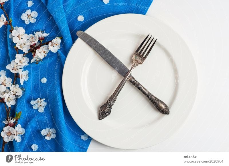 Crossed knife and fork on an empty white plate Lunch Dinner Plate Cutlery Knives Fork Table Kitchen Restaurant Flower Wood Metal Steel Old Eating Above Retro