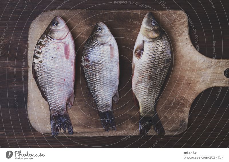 Three fresh river crucian on a kitchen board Fish Diet Wood Old Eating Retro Brown food three cook Live vintage Edible scales whole Tasty Top cooking