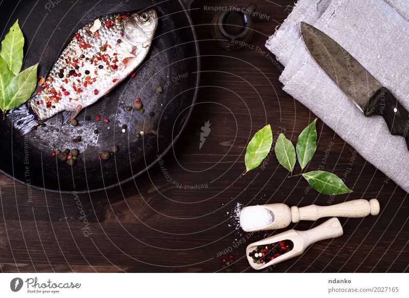 fish crucian in a cast-iron frying pan with spices Fish Herbs and spices Nutrition Pan Spoon Table Kitchen Eating Fresh Delicious Retro Brown Black salt pepper