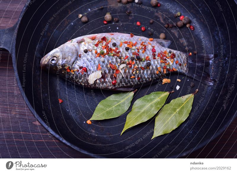 Carp with spices in a black cast-iron frying pan Fish Herbs and spices Pan Table Kitchen Nature Leaf Wood Eating Fresh Above Brown Green Black crucian pepper