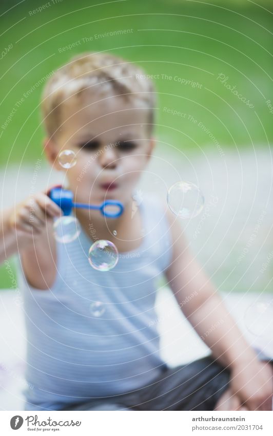 Boy blowing soap bubbles in the meadow Leisure and hobbies Playing Vacation & Travel Trip Summer vacation Garden Human being Masculine Child Boy (child) Infancy