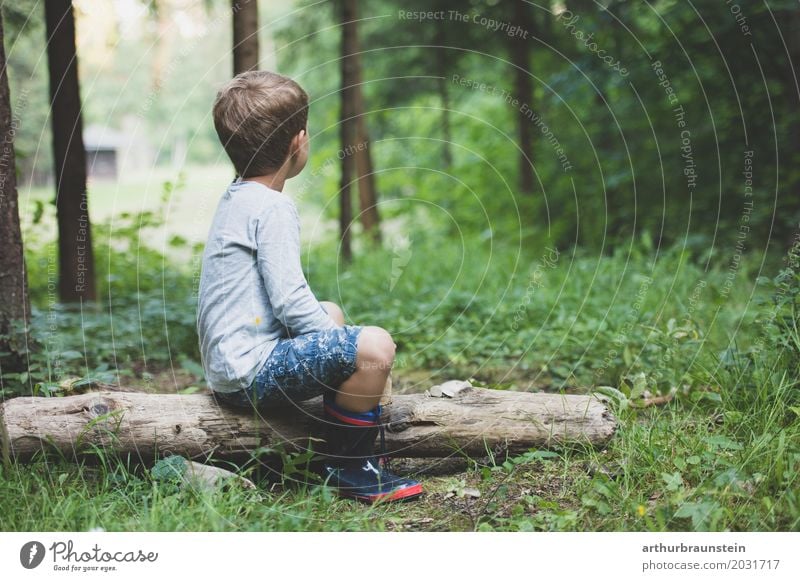 Boy in rubber boots sits on tree trunk in nature Leisure and hobbies Playing Vacation & Travel Tourism Trip Adventure Hiking Kindergarten Child School