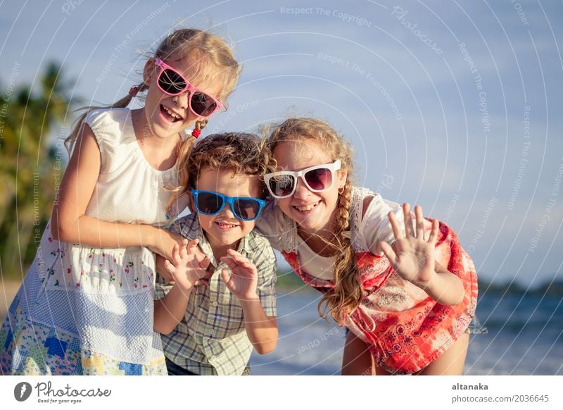 Three happy children standing on the beach at the day time. People having fun outdoors. Concept of friendly family and of summer vacation. Lifestyle Joy Happy