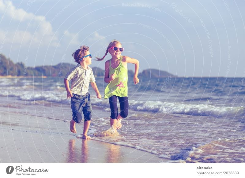 Happy children playing on the beach at the day time. Lifestyle Joy Relaxation Leisure and hobbies Playing Vacation & Travel Adventure Freedom Summer Sun Beach