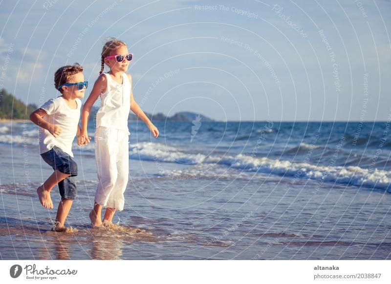 Happy children playing on the beach at the day time. Lifestyle Joy Relaxation Leisure and hobbies Playing Vacation & Travel Adventure Freedom Summer Sun Beach
