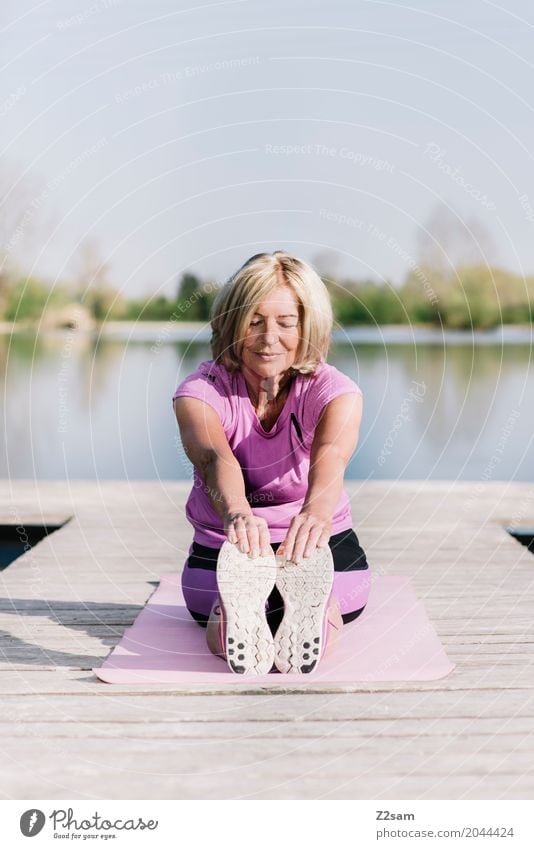 Woman doing yoga by the lake Lifestyle Leisure and hobbies Fitness Sports Training Warming up Yoga Female senior 60 years and older Senior citizen Landscape