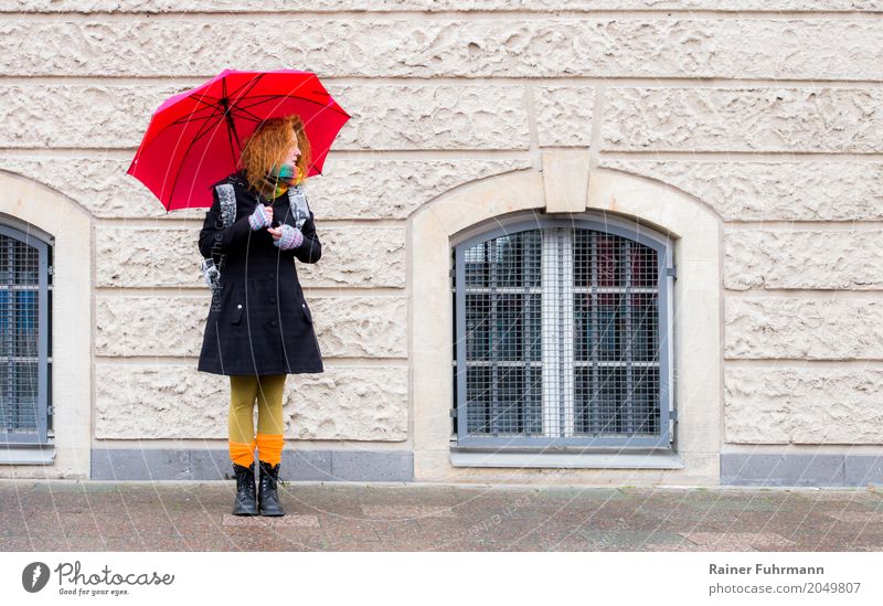 a woman stands with an umbrella and waits Human being Feminine Woman Adults 1 Town Pedestrian Coat Accessory Umbrella Long-haired Stand Wait "Weather Facade sad