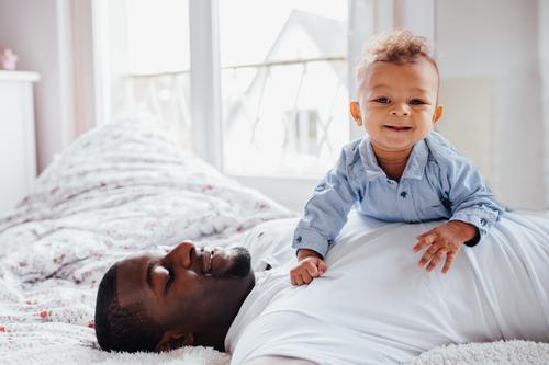 Young Afro-American dad and toddler cuddle together Lifestyle Joy Happy Bedroom Human being Masculine Baby Toddler Boy (child) Young man Youth (Young adults)